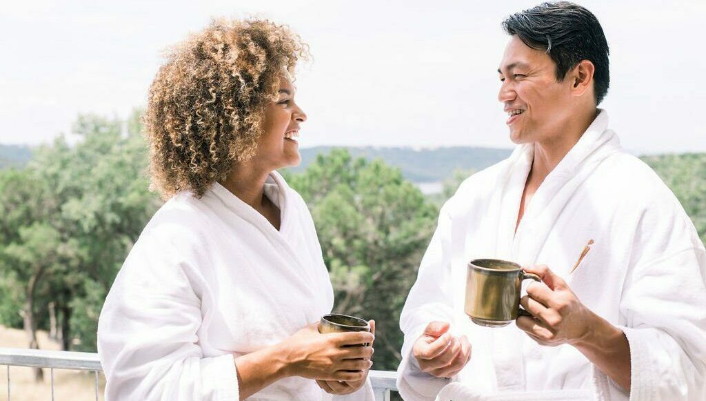 two people holding cups and smiling at eachother