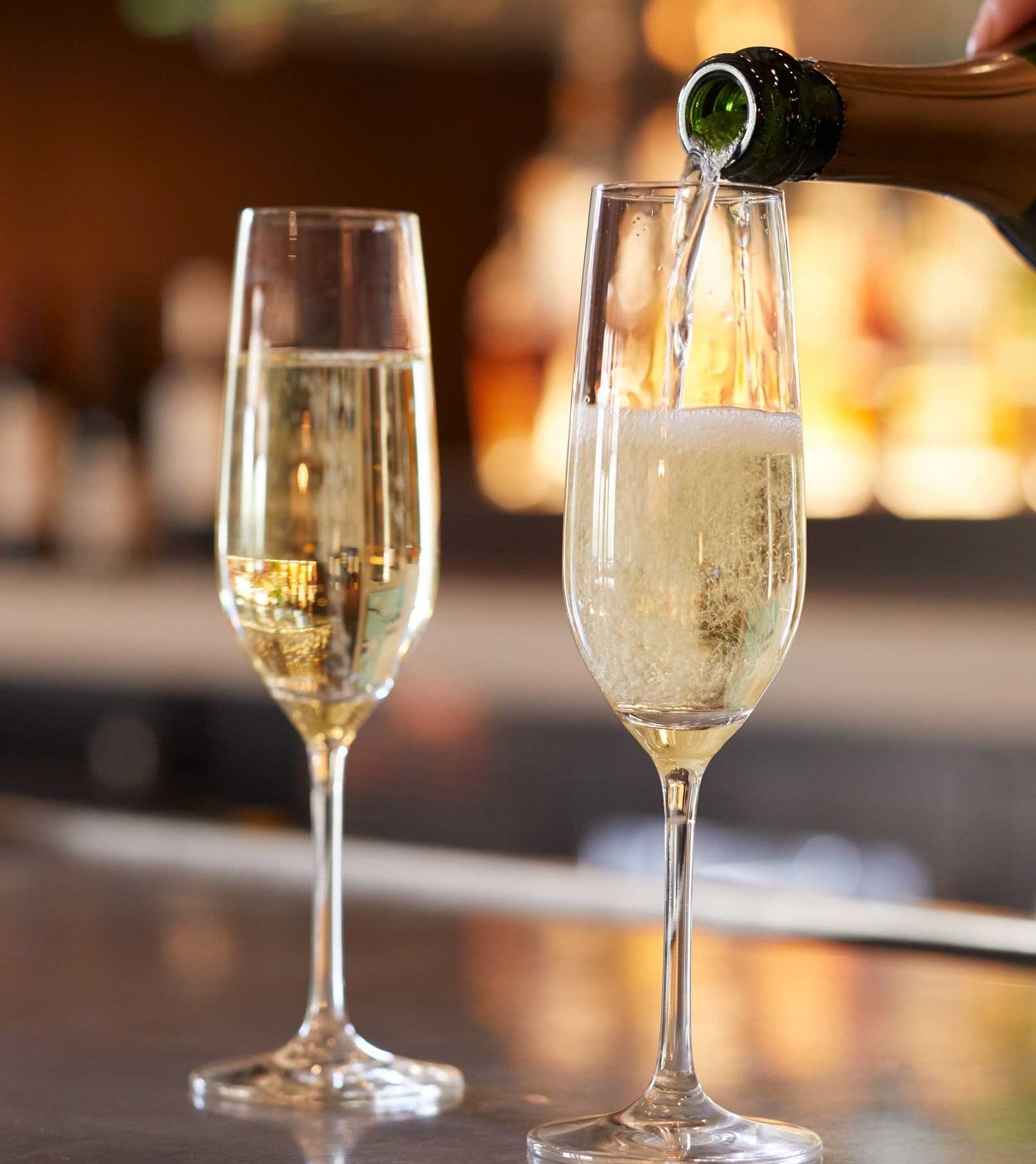 person pouring champagne into glass