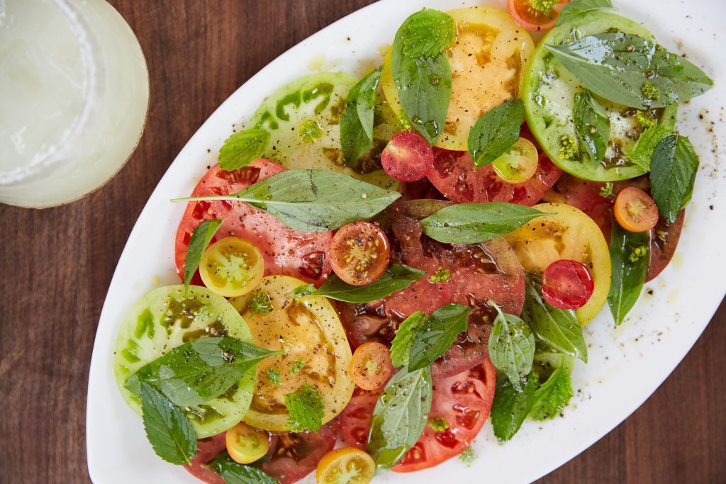 Colourful tomato and basil salad on white plate