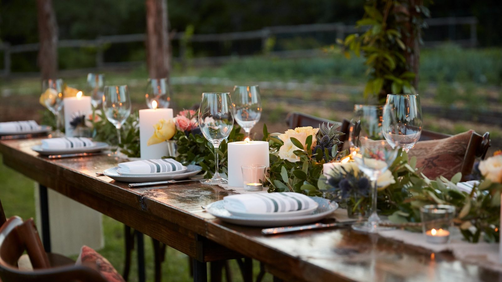 long wooden dinner table with floral and plating decorations