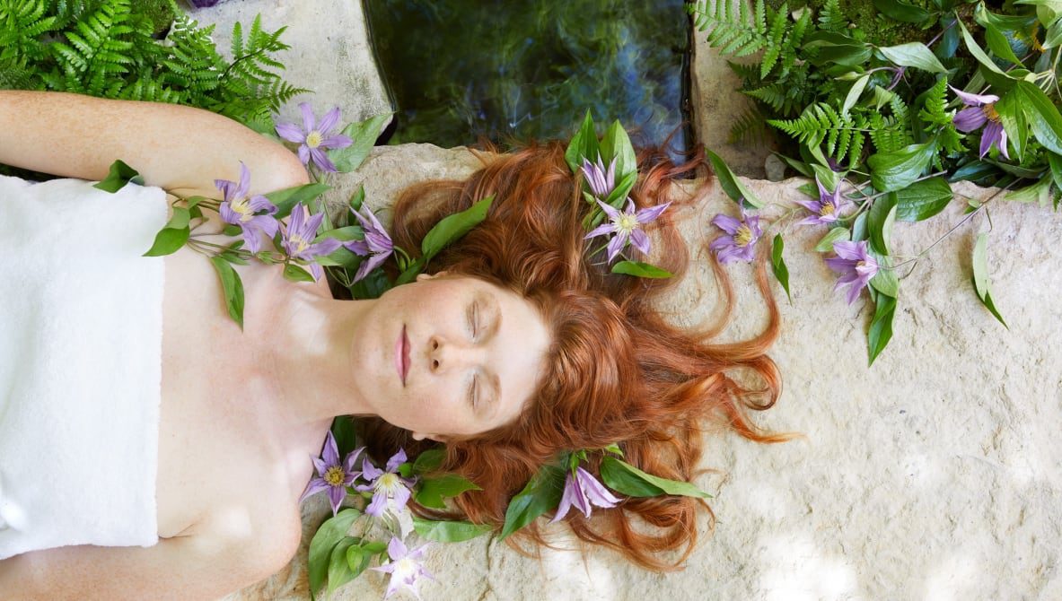 person relaxed with eyes closed and flowers around