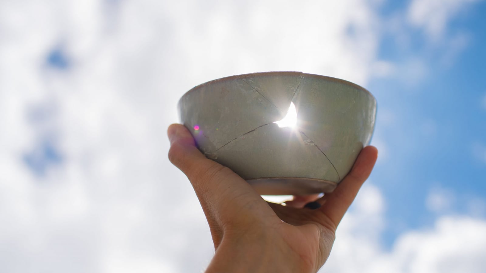 person holding bowl with cracks and a hole