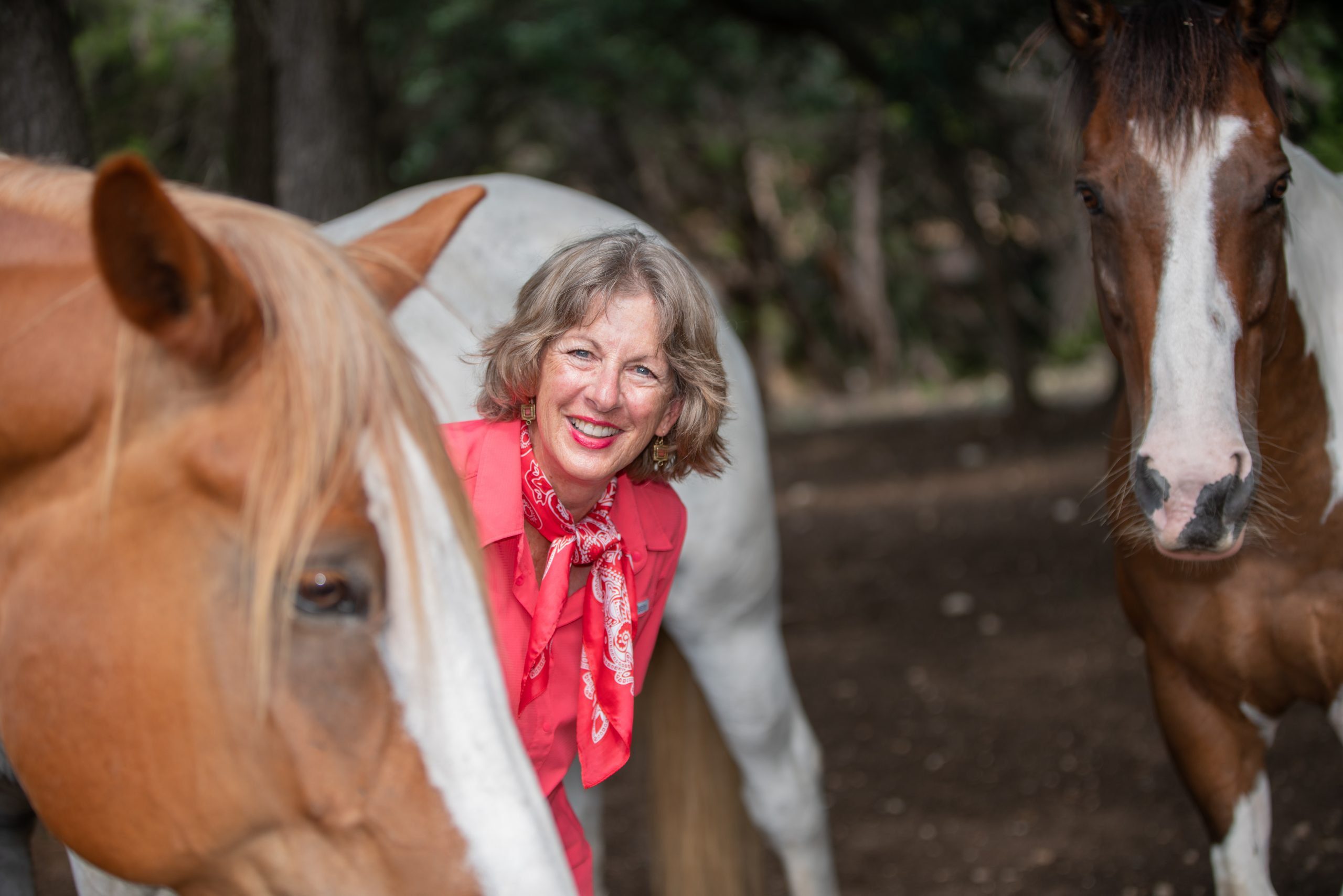 person smiling beside two horses