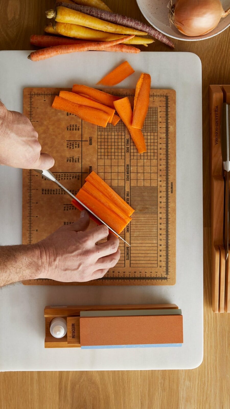 person cutting carrots on a measuring board