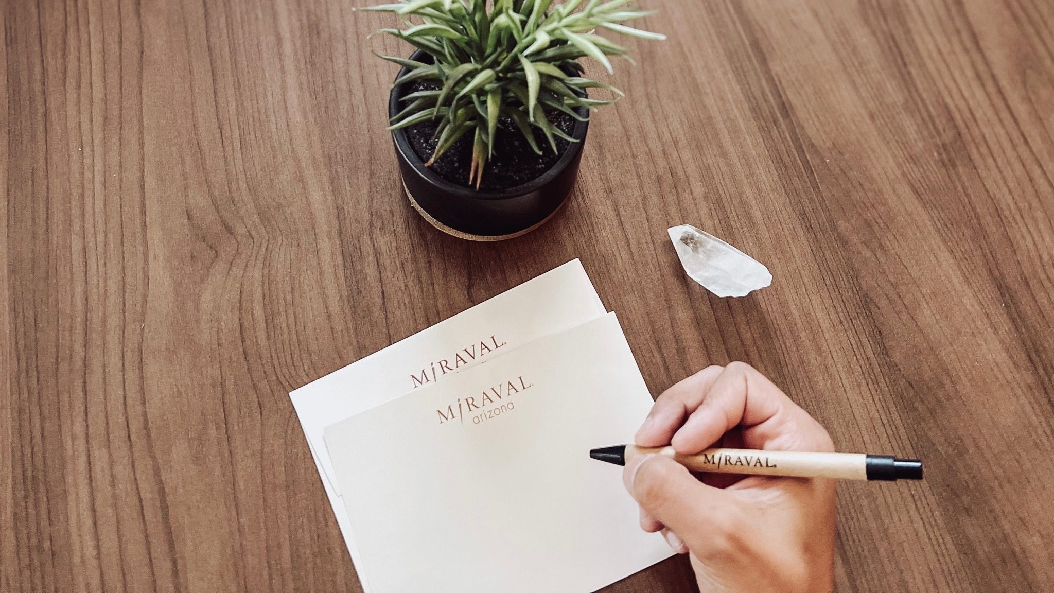 Person writing note on Miraval notepad with Miraval pen