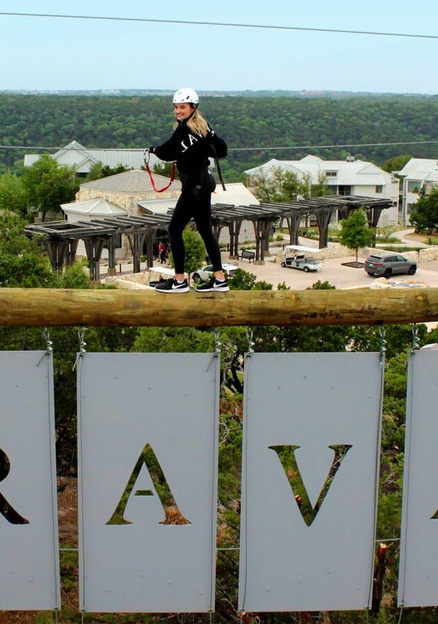 person supported by rope walking across a miraval beam