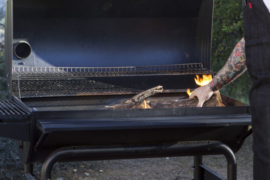 person putting a log into a bbq