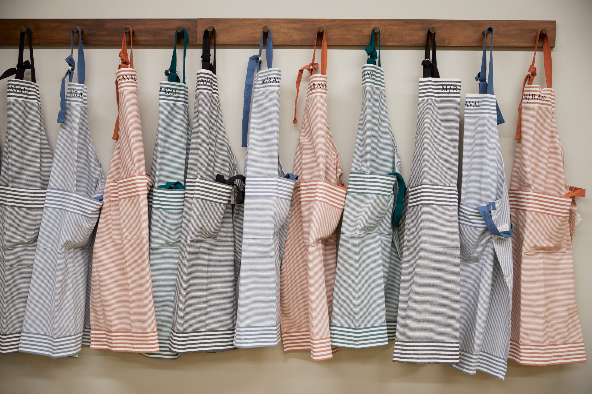 Miraval aprons in different colours hanging on wardrobe