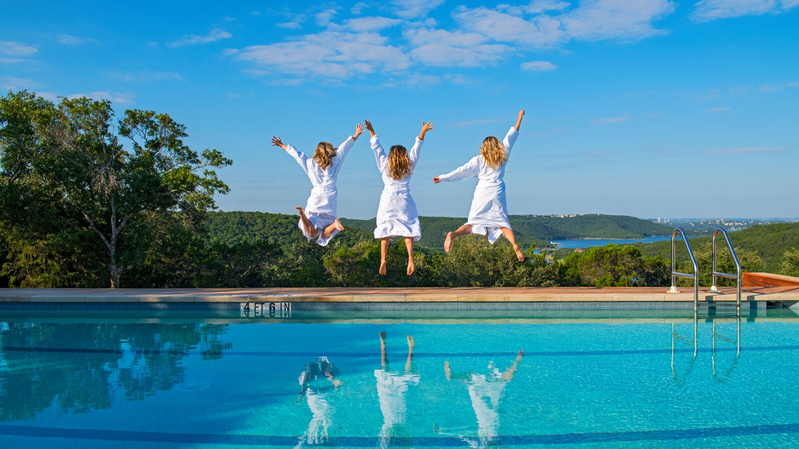 3 people jumping beside a pool