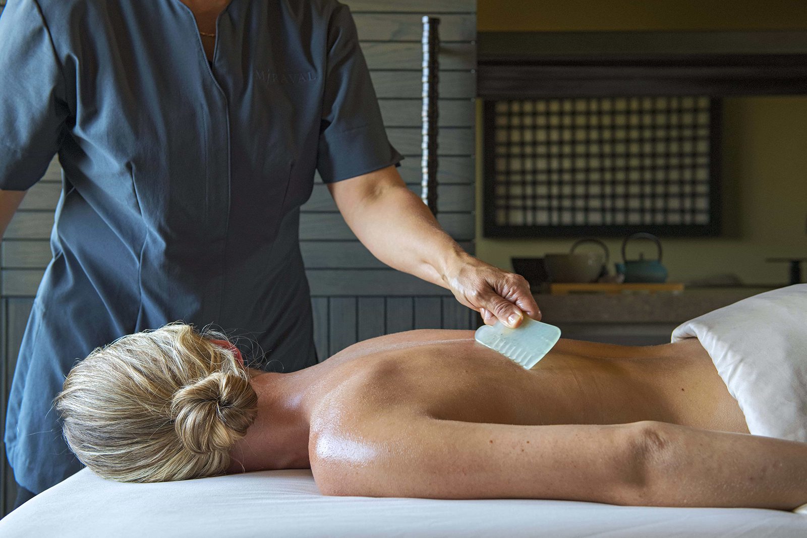 person giving someone a back massage using a tool