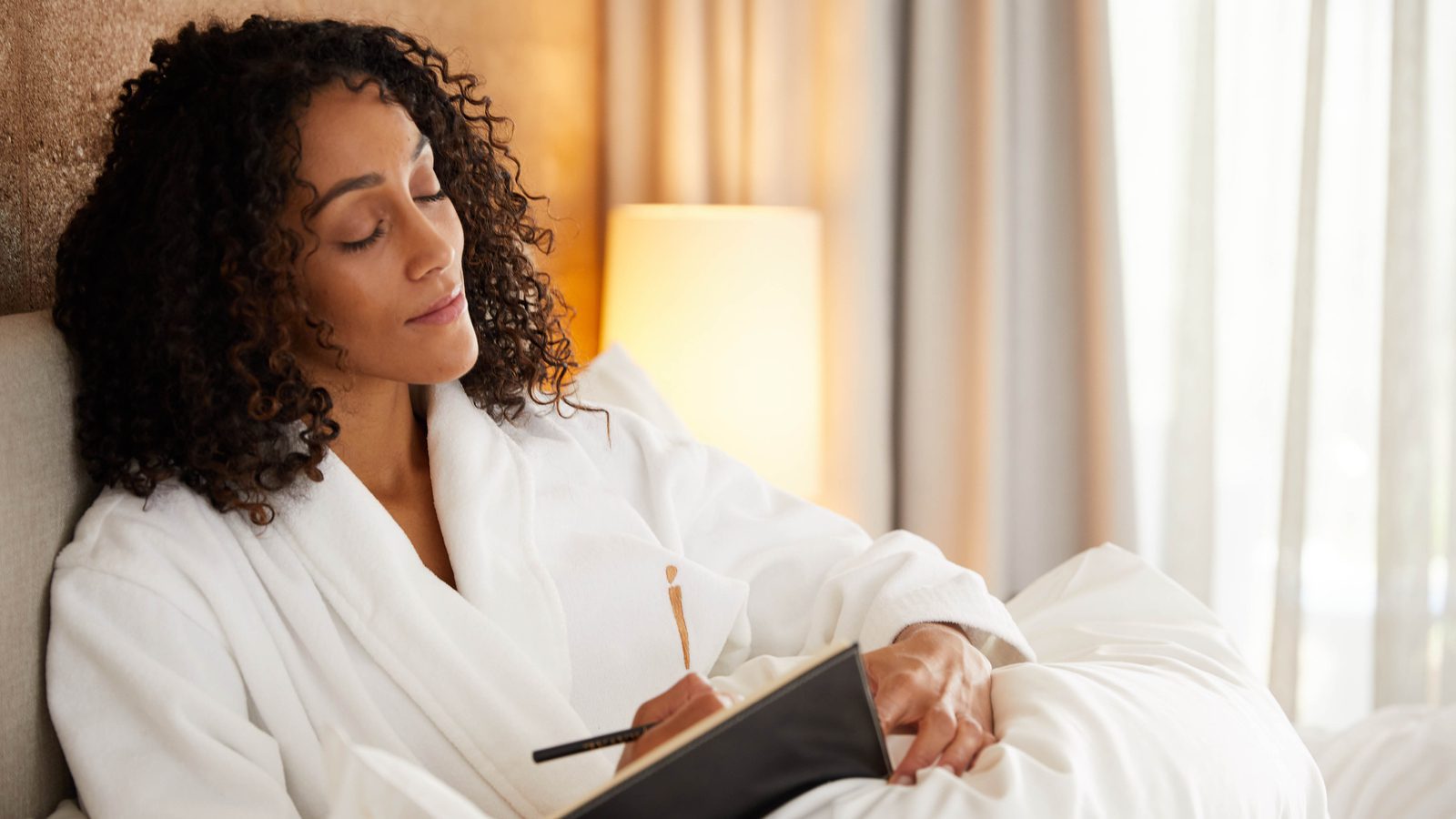 person relaxed in a robe writing in a journal