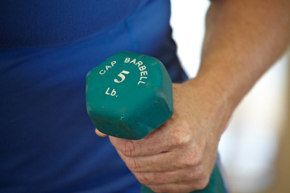 person carrying 5 pound barbell